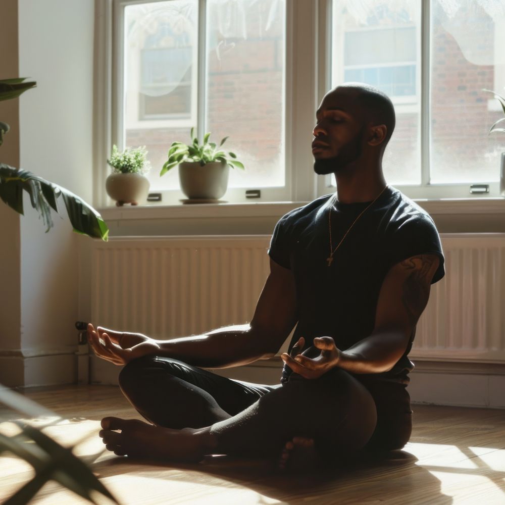man practicing yoga in a bright living room with large windows.