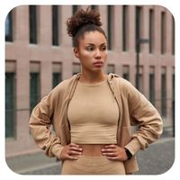Woman in a beige outfit standing outdoors with a blurred background